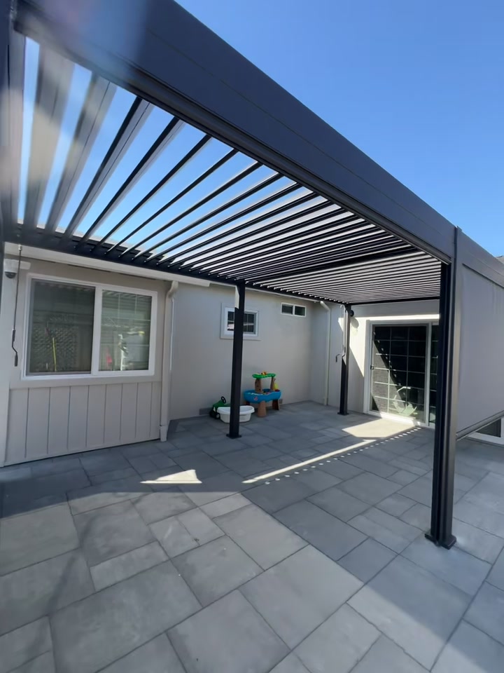 Recent project walkthrough — finished black louvered patio cover over a tiled backyard patio
